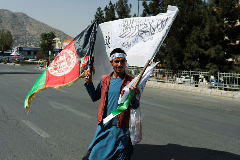 An Afghan man sells the flags of the former Afghan government and the Islamic Emirate of Afghanistan during the anti-Pakistan protest in Kabul on September 7, 2021 [West Asia News Agency via Reuters]